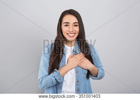 Beautiful Grateful Woman With Hands On Chest Against Light Grey Background