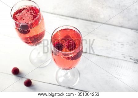 Kir Royal Champagne Cocktail On White, Copy Space. Flute Glasses With Berry Sparkling Champagne Drin