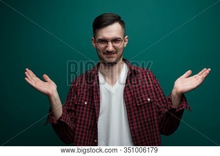 Portrait Of A Chherful Young Man In Glasses Posing Against A Green Background.