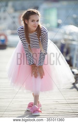 Happy Young Womanl With A Long Braid Happy Laughing While Sitting Outdoor With Boats On Background. 