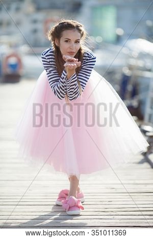 Happy Young Womanl With A Long Braid Happy Laughing While Sitting Outdoor With Boats On Background. 