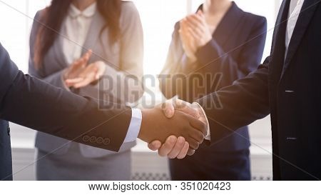 Partnership Concept. Multicultural Men Shaking Hands After Sealing The Deal, Women Clapping In The B