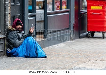 London, England, Uk - January 2, 2020: A Bearded Man Sitting On The Sidewalk And Begging From Passer