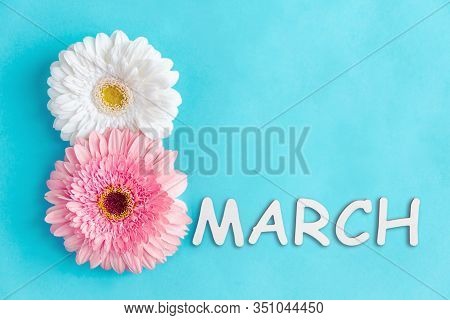 Inscription 8 March Made Of Two Pink And White Gerbera Flowers On Blue Background. Greeting Card Tem
