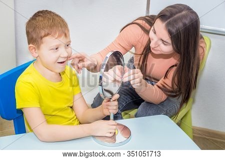 Speech Therapy. A Young Speech Therapist Is Engaged In Cubes With A Boy. Learning The