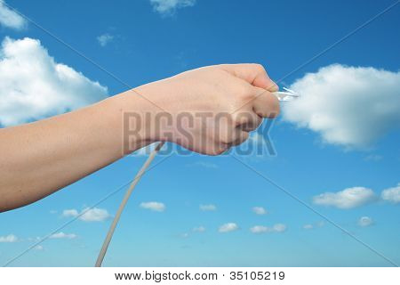 Konceptet eller begreppsmässig mänskliga eller man hand håller en internet-datakabel i moln över den blå himlen, en