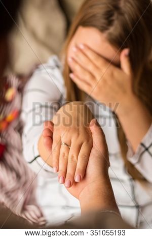 A Mans Hand Holds A Womans Hand. The Girl Has An Engagement Ring With A Diamond. In The Background, 