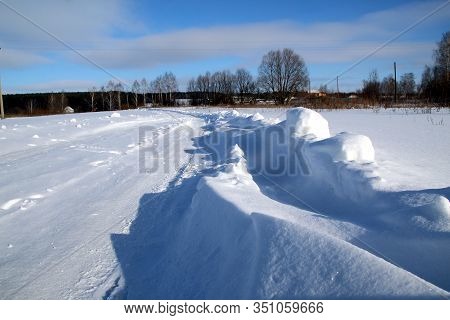 Winter Road On A Sunny Day With Snowdrifts Along The Edges