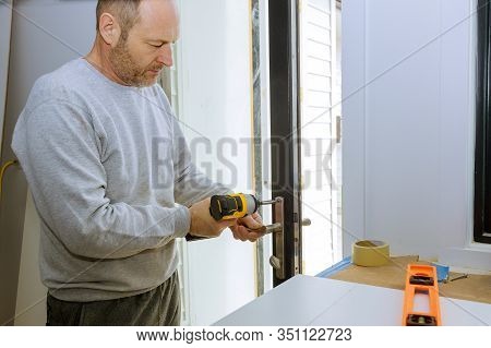 Closeup Of A Professional Locksmith Installing Or Repairing A New Deadbolt Lock On A House Door With