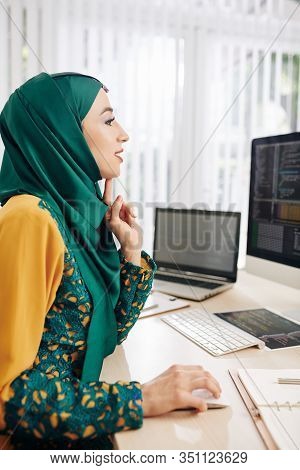Excited Female Programmer Sitting At Office Desk And Writing Code For Mobile Application