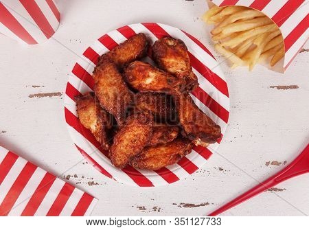 Perfect chicken wings in red white stripes plate meal with french fries and soft drink view from above