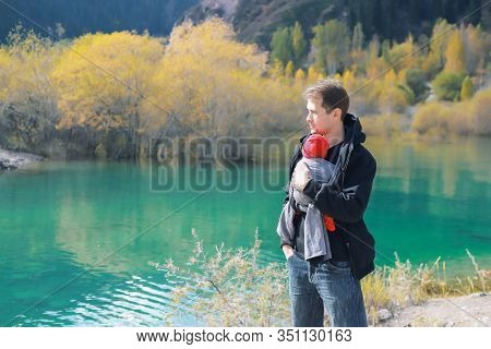 Attractive Young Father With Her Infant Baby In Sling Outdoor. Man Is Carrying Her Child And Travel 