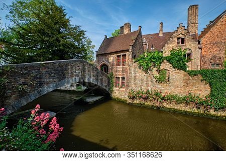 Old Bonifacius Bridge over Brugge canal and medieval houses with flowers in Bruges, Belgium