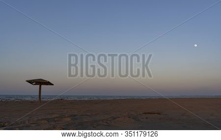 Caspian Sea With Beach And  Wooden Beach Umbrella With Moon In The Evening.