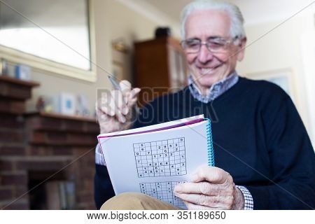 Senior Man Doing Sudoku Puzzle At Home