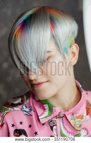 Portrait Of A Young Beautiful Girl In A Pink Shirt On A Gray Background With Dyed Hair. Short Haircu