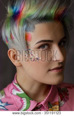 Portrait Of A Young Beautiful Girl In A Pink Shirt On A Gray Background With Dyed Hair. Short Haircu