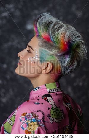 Portrait Of A Young Beautiful Girl In A Pink Shirt On A Gray Background With Dyed Hair. Short Haircu
