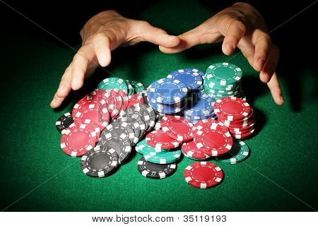 Poker fişleri ve yeşil masa üstündeki elleri