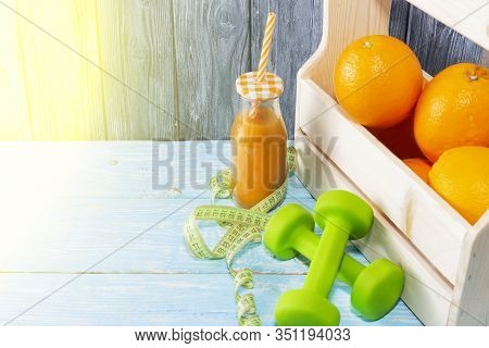Lots Of Oranges And A Bottle Of Juice, Dumbbells, Measuring Tape On A Wooden Textured Background. Fi