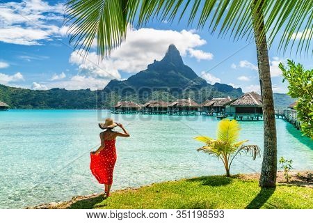 Tahiti travel holiday luxury hotel vacation tourist woman walking on Bora Bora island beach with view of Mt Otemanu in French Polynesia. High end resort with overwater bungalows villas.