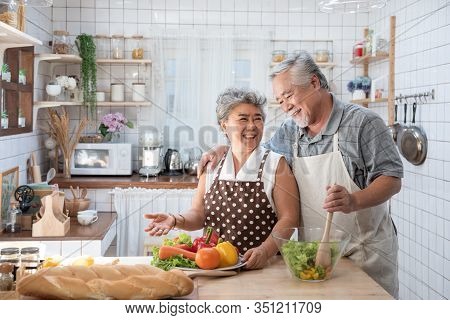 Senior Couple Having Fun In Kitchen With Healthy Food - Retired People Cooking Meal At Home With Man