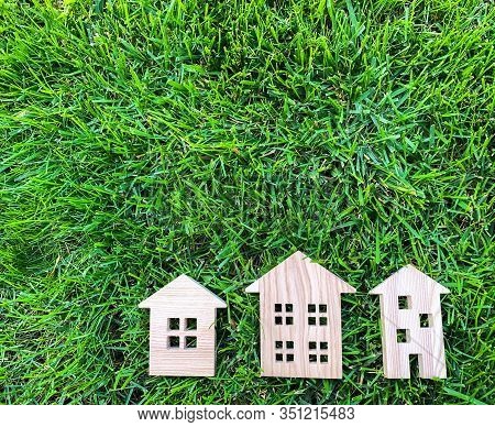 Miniature Wooden Houses On Green Grass. Real Estate Concept. Modern Housing. Eco-friendly And Energy