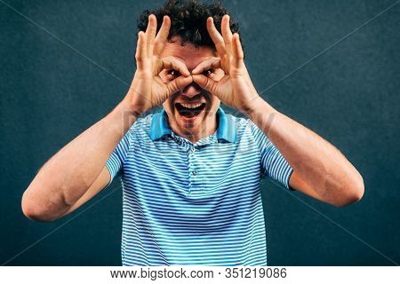 Funny Young Man Posing For Advertisement, Smiling And Making A Grimace, Standing At Building Gray Wa