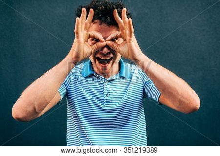 Funny Young Man Posing For Advertisement, Smiling And Making A Grimace, Standing At Building Gray Wa