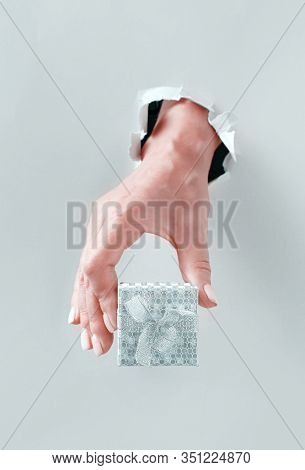 Hand Keeping Gift Box  From Grey Torn Paperr Close Up