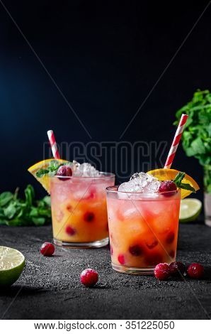 Cocktail With Rum Or Vodka, Soda, Cranberry, Orange Juice, Lime And Mint In The Glass On Dark Grey B