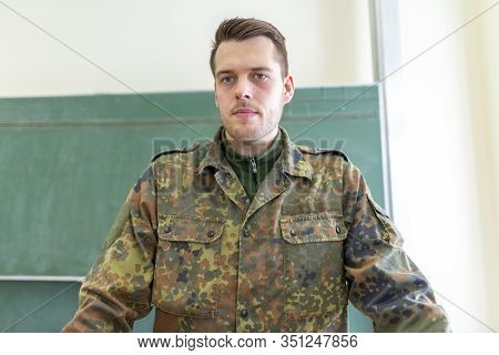 German Soldier Stands In A Classroom . German Word Bundeswehr, Means German Army.