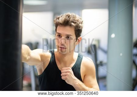 Man training on the punching bag with his bare hands in a gym