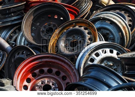 Old Hubcaps With No Logo. Some Rusty, Some Not. In A Heap And Abandoned. Red One In Front.