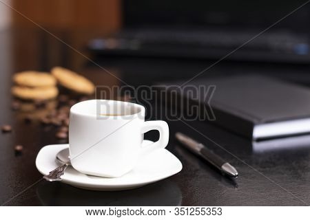 Fresh Cup Of Cappuccino In A White Cup Of Coffee, Table With A Pwn And A Notebook