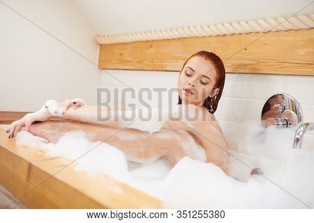Portrait of redhaired woman playing with foam in bathtub