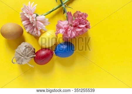 Colorful Easter Eggs With Bright Colorful Spring Flowers On The Yellow Background. Top View. View Fr