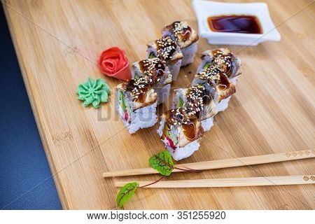 Japanese Sushi Food On A Wooden Board. Salmon, Rice, Wasabi, Ginger, Chopsticks Hashi Japanese Cuisi