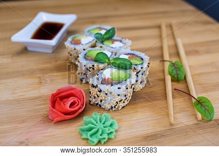 Japanese Sushi Food On A Wooden Board. Salmon, Rice, Wasabi, Ginger, Chopsticks Hashi Japanese Cuisi