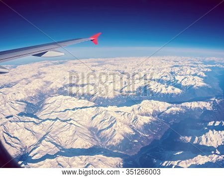Beautiful Fly Over Winter Alps Mountains. Clouds With Blue Sky, Through Airplane Window, Aircraft Wi