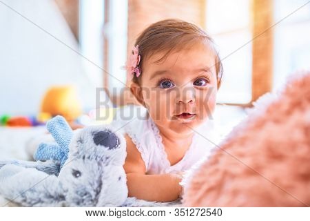 Beautiful infant happy at kindergarten around colorful toys lying on blacket
