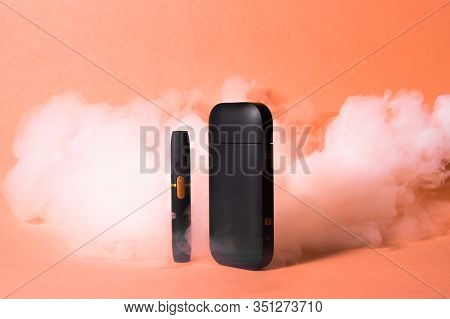 Iqos Electronic Cigarette In Smoke On An Orange Background.