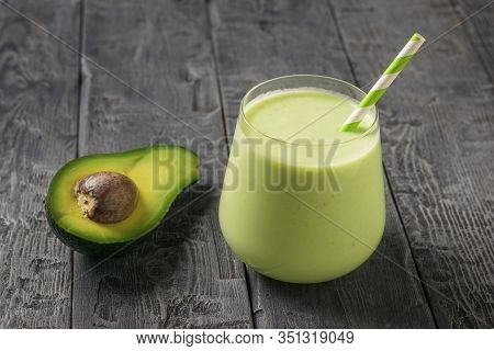 Half An Avocado And A Glass Glass With A Smoothie And A Cocktail Tube On A Wooden Table. Fitness Pro