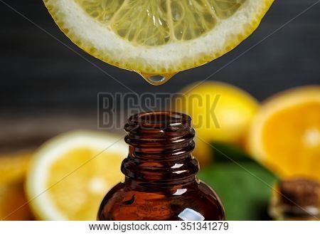 Citrus Essential Oil Dripping From Lemon Slice Into Bottle, Closeup
