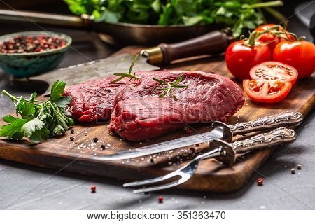 Two Beef Rump Steaks With Herbs Tomatoes Salt And On Butcher Board.