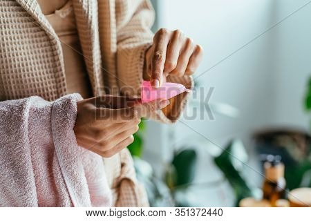 Close Up Of Woman Hand Folding Menstrual Cup Showing How To Use, C Form. Women Health Concept. How T