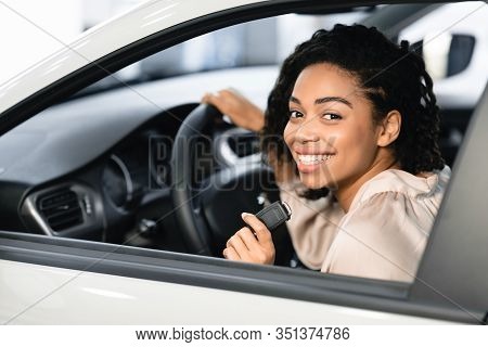 Buying New Car. Happy Lady Doing Test Drive Posing With Auto Key Sitting In Automobile In Dealership