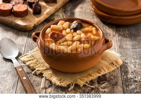 Typical Spanish Fabada Asturiana In Crockpot On Wooden Table