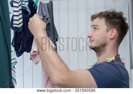 Portrait Of A Man About 30 Years Old With A Beard, Hangs His Clothes On A Clothesline, Leads A Bache