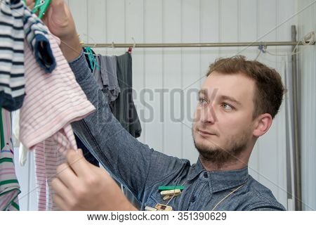 Portrait Of A Man About 30 Years Old With A Beard, Hangs His Clothes On A Clothesline, Leads A Bache